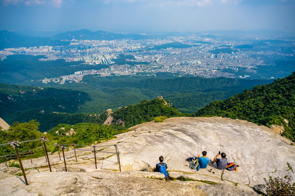 북한산 백운대에 암반 지대에 앉아 서울의 풍경을 감상하는 등산객 모습.